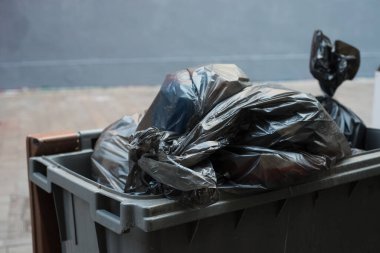 Sokaktaki bir çöp konteynırının içinde plastik poşetlerin yakın plan fotoğrafı.
