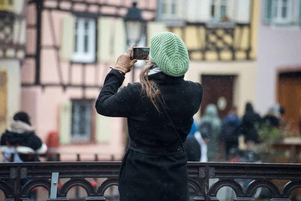 游客用她的智能手机在法国科尔玛拍照的背景图片 — 图库照片