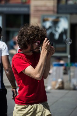 Strasbourg - Fransa - 14 Mayıs 2022 - Teeshirt 'li fotoğrafçının portresi sokakta sabun köpüklerinin fotoğrafını çekiyor  