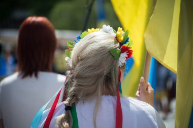 Arka planda Ukrayna bayrağı taşıyan kadının portresi ve kafasında çiçekler savaşı protesto ediyor. 