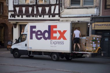 Strasbourg - Fransa - 11 Haziran 2022 - Moda mağazasının yakınına park etmiş Fedex dağıtım kamyonundan malları getiren teslimatçı