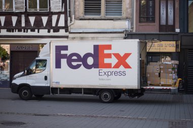 Strasbourg - Fransa - 11 Haziran 2022 - Moda mağazasının yakınına park etmiş Fedex dağıtım kamyonundan malları getiren teslimatçı
