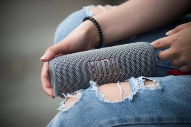 Mulhouse - Fransa - 16 Haziran 2022 - Gri taşınabilir JBL subwoofer hoparlörü sokaktaki genç kadının ellerinde