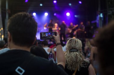 Mulhouse - Fransa - 21 Haziran 2022 - Sokaktaki bir konser sırasında akıllı telefonlu kişilerin arka planda portresi 