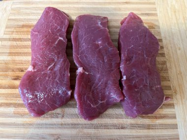 Tahta bir tahtanın üzerinde duran uzun bir et kasından yapılmış biftek.