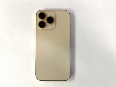 Beyaz izole edilmiş arka planda üç kameralı modern altın renkli telefon.