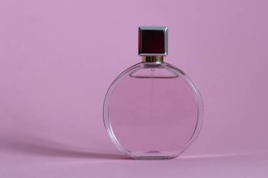Pembe bir kutudan çıkan parfüm şişesi izole bir arka planda, maket ve kopyasal alan ile birlikte.