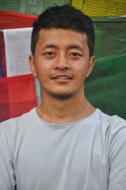 Ladakhi 'nin genç bir delikanlının kameraya bakıp Budist dua bayraklarının önünde durduğunu gördüm.  