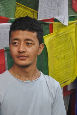 Ladakhi 'li bir delikanlının yandan bakması, Budist dua bayraklarına karşı durması.  