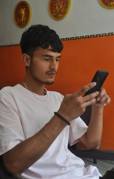 Yakışıklı Bir Hintli Genç Içeride Sandalyede Otururken Telefonunu Kullanıyor — Stok fotoğraf