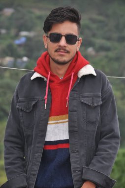 Güneş gözlüğü takan, dışarıda kameraya bakan yakışıklı bir gencin portresi. 