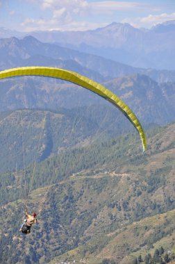 Kimliği belirsiz erkek gezginin Himachal Pradesh 'te profesyonel pilotla yamaç paraşütü yaparken görüntüsü.