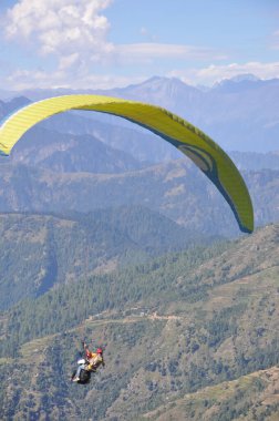 Kimliği belirsiz erkek gezginin Himachal Pradesh 'te profesyonel pilotla yamaç paraşütü yaparken görüntüsü.