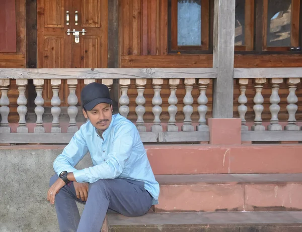 A north Indian young guy looking sideways while sitting on temple stairs with copy space