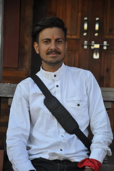 一个快乐的印度年轻人坐在庙宇里看着相机 — 图库照片