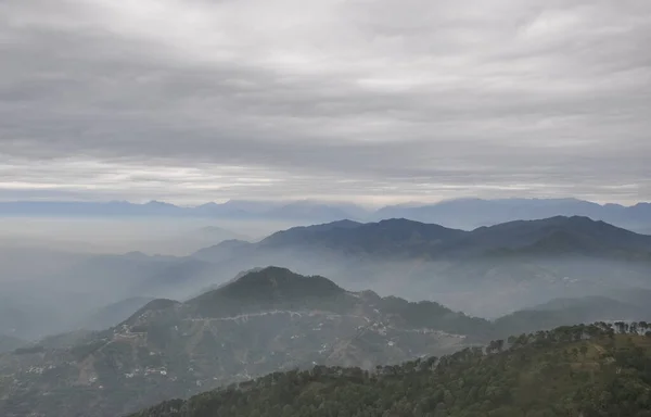 Beautiful layers of mountains covered with fog in cloudy weather after rain