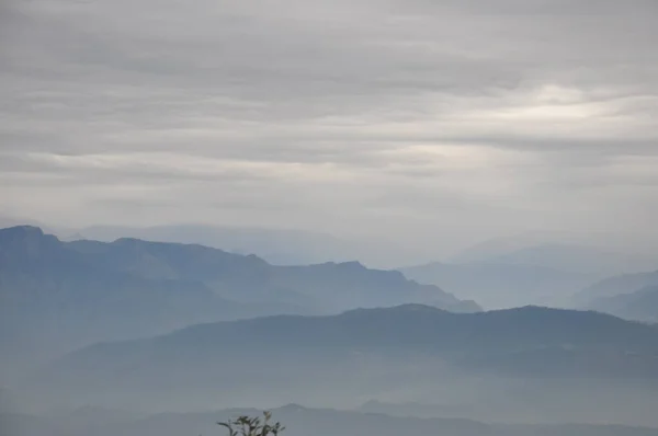 Layers of beautiful blue mountains with fog and cloudy weather after rain