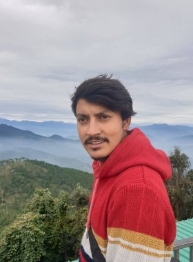 Close-up of a young guy looking sideways while standing against the background of mountains