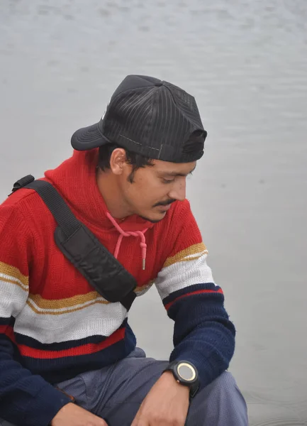 Young Guy Wearing Cap Backwards Looking While Sitting Next Lake — Foto Stock