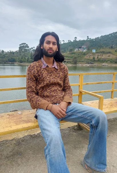 Симпатичный Индийский Молодой Человек Длинными Волосами Бородой Смотрящий Камеру Сидя — стоковое фото