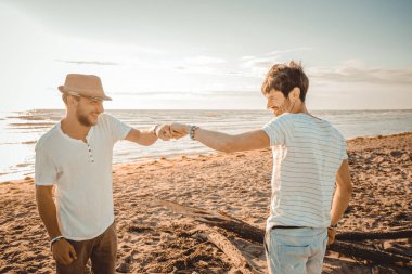 Kumsalda birbirini yumruk tokuşturarak selamlayan iki beyaz adam konsept buluşuyor, saygı ve dostluk gösteriyorlar iyi ilişkiler kuruyorlar.