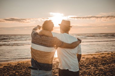 İki arkadaş sahilde gün batımına bakarak birbirlerine sarılırlar. Arkadaşlık ve aşk kavramı