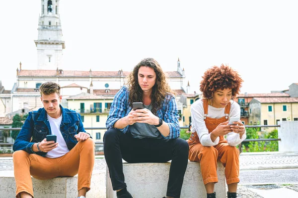 携帯電話を使って友達を作る多文化グループ 列に座り スマートフォンで入力する学生 — ストック写真