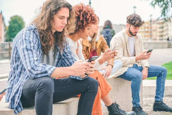 携帯電話を使って友達を作る多文化グループ 列に座り スマートフォンで入力する学生 — ストック写真