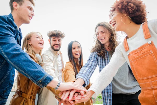 Portrait of happy university friends stacking hands together, showing unity and togetherness - Diverse Culture Students Celebrating Together - Friendship concept