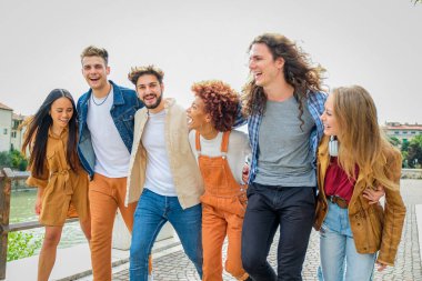 Bir grup mutlu genç arkadaş şehir caddesinde yürüyor ve konuşuyor - üniversite öğrencileri birlikte yürüyor ve eğleniyorlar - turizm, seyahat ve eğlence kavramı