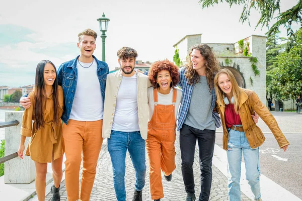 Bir grup mutlu genç arkadaş şehir caddesinde yürüyor ve konuşuyor - üniversite öğrencileri birlikte yürüyor ve eğleniyorlar - turizm, seyahat ve eğlence kavramı