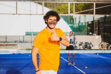 Gülümseyen genç Padel oyuncusunun parmaklarıyla imza atması - Padel 'de ya da tenis maçında kazandığı zaferden sonra başparmağını gösteren mutlu yakışıklı adam
