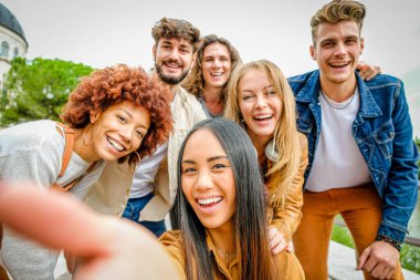 Çok ırklı mutlu arkadaşlar birlikte eğleniyor ve gülüyorlar. Şehir sokaklarında selfie çekiyorlar. Mutlu bir yaşam tarzı ve arkadaşlık konsepti.