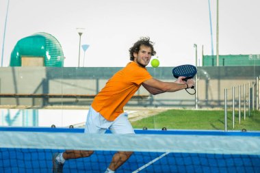 Padel, mavi çim padel sahasında maç yapıyor - Yakışıklı bir çocuk bir maç oynuyor