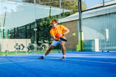 Padel, mavi çim padel sahasında maç yapıyor - Yakışıklı bir çocuk bir maç oynuyor