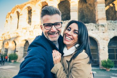 Mutlu bir çift yaşlı turist İtalya 'nın ünlü anıtının önünde selfie çekerken eğleniyor - tatil, turizm ve seyahat kavramı