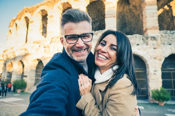 Mutlu bir çift yaşlı turist İtalya 'nın ünlü anıtının önünde selfie çekerken eğleniyor - tatil, turizm ve seyahat kavramı