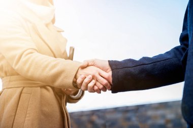 Şehirdeki ofis binalarının önünde iş ortağıyla tokalaşan işadamı - selamlama, anlaşma, birleşme ve satın alma kavramları