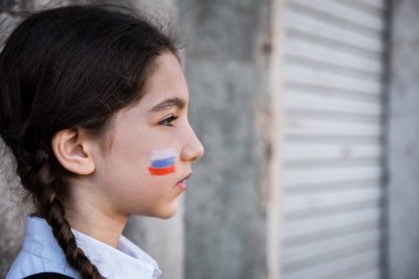 Yüzünde Rus renkleri olan üzgün bir kızın portresi. Barış ve koruma çocuk kavramı