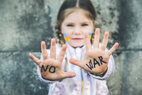 Beautiful and scared child inscription NO WAR on his hands. Russia's invasion of Ukraine, kids against the war