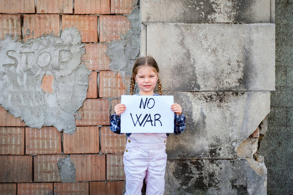 Child girl holding a poster with written NO WAR in support of peace. Concept of "no war" in Ukraine and in the world. Russian conflict in support of peace
