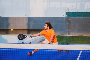 Padel, mavi çim padel sahasında maç yapıyor - Yakışıklı bir çocuk bir maç oynuyor