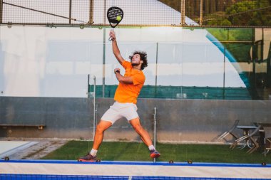 Padel, mavi çim padel sahasında maç yapıyor - Yakışıklı bir çocuk bir maç oynuyor