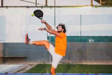 Padel, mavi çim padel sahasında maç yapıyor - Yakışıklı bir çocuk bir maç oynuyor
