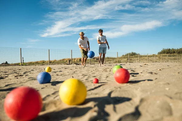 Turistler aktif bir oyun oynuyor, Petanque deniz kenarındaki kumlu bir sahilde - plaj tatillerinde bulvarda oynayan bir grup genç - toplar yerde