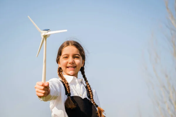 Child playing and looks interested at a wind turbine toy - Concept of future generation and enewable Energy