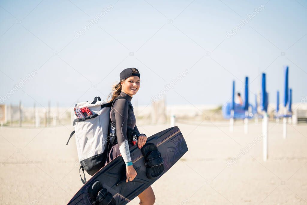 Beautiful girl smiling and comes to the beach with kitesurfing equipment - Sporty woman concept and hard sport