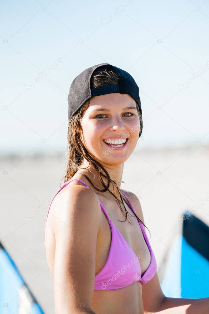 Portrait of kite surfing girl smiling in swimsuit with kitesurf on the beach. Water sports, and sporty woman concept