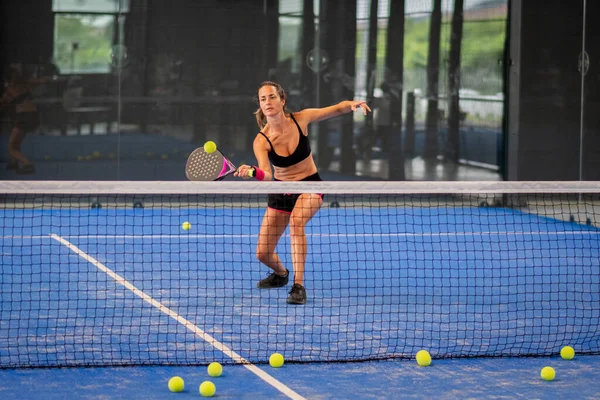 女人在蓝色草场打羽毛球 年轻的运动女子羽毛球手用球拍击球 免版税图库照片