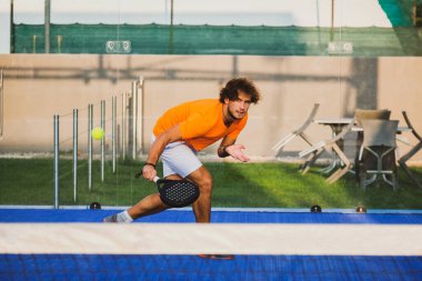 Padel, mavi çim padel sahasında maç yapıyor - Yakışıklı bir çocuk bir maç oynuyor
